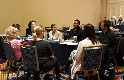 Participants sit around a table and talk. Participants sit around a table and talk.