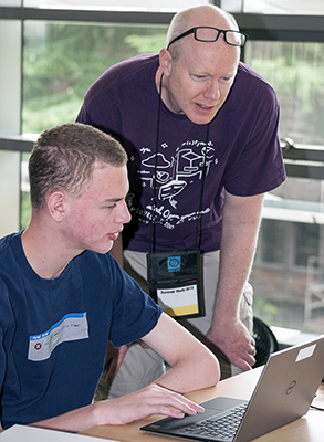 An educator helps a student on a computer. An educator helps a student on a computer.