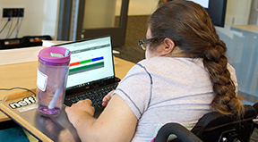 A student in a wheelchair uses a laptop. A student in a wheelchair uses a laptop.