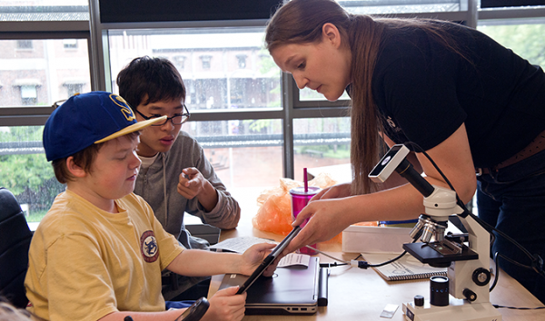 An educator shows two students how data is displayed on a tablet