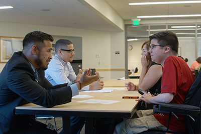 An instructor discusses across a table with a high school student.